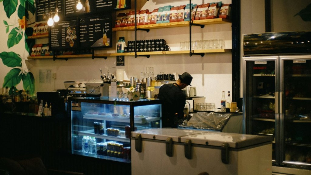Barista bereidt koffie in een sfeervolle lokale koffiezaak met volle schappen en warme verlichting