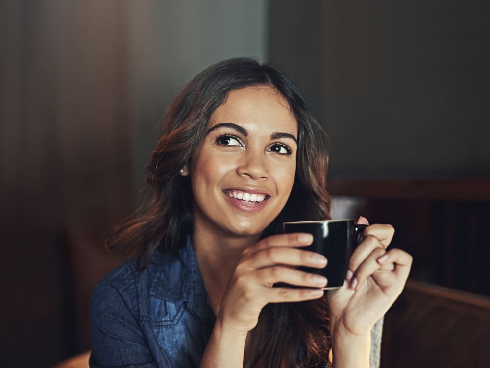 lachende vrouw geniet van een lekkere kop koffie